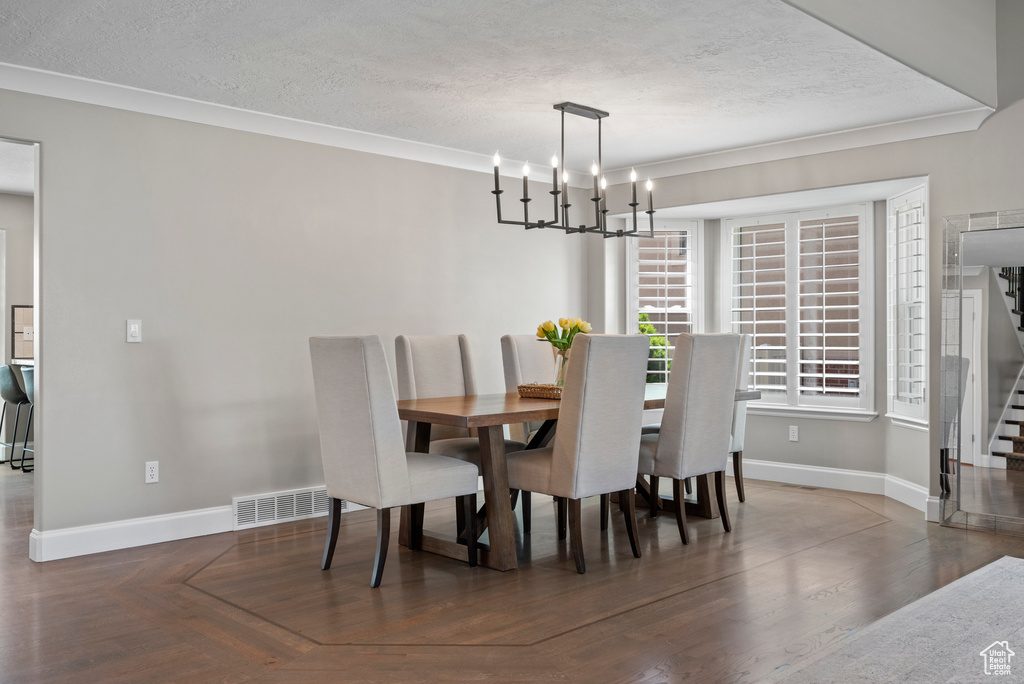 Dining space featuring a textured ceiling, stairs, baseboards, a chandelier, and ornamental molding