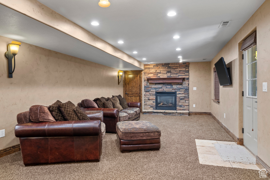 Carpeted living room with a stone fireplace and recessed lighting