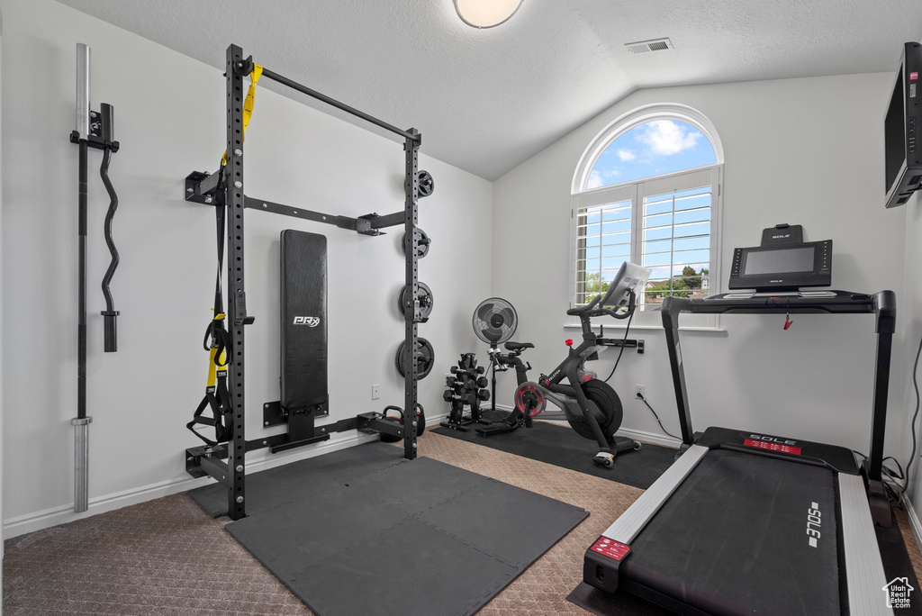 Exercise area with vaulted ceiling and baseboards