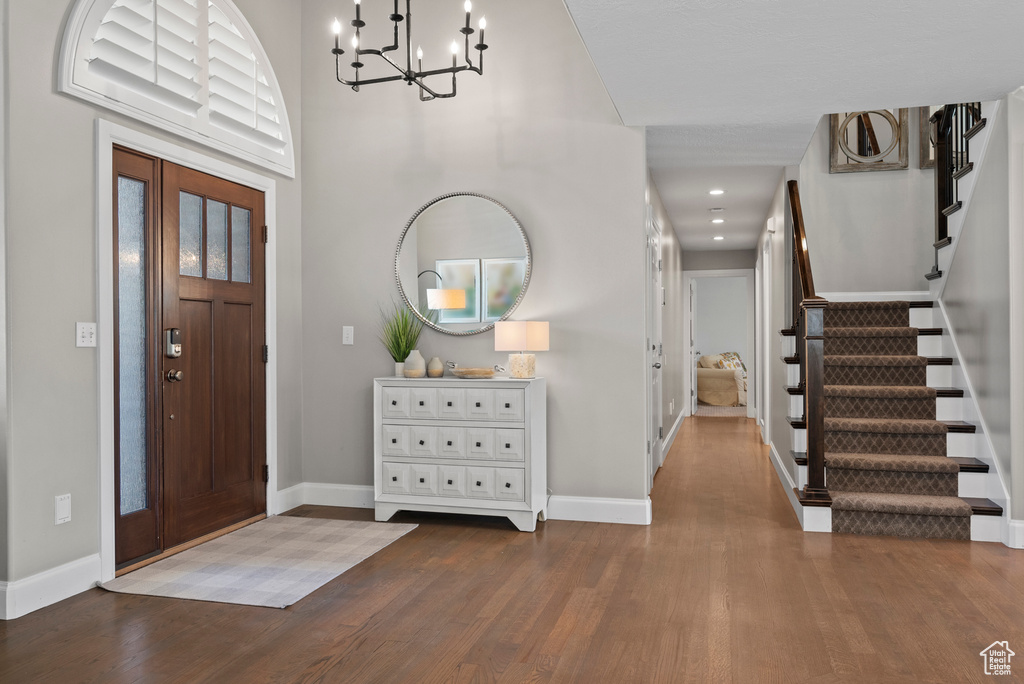 Foyer entrance featuring wood finished floors, baseboards, stairway, a chandelier, and recessed lighting