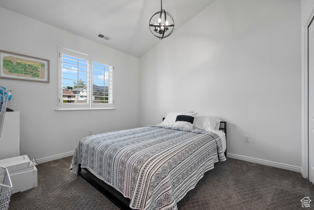 Carpeted bedroom featuring a chandelier, vaulted ceiling, and baseboards