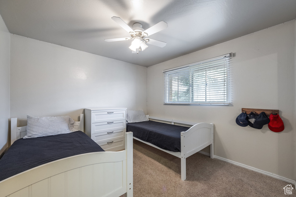 Bedroom featuring light carpet, a ceiling fan, and baseboards
