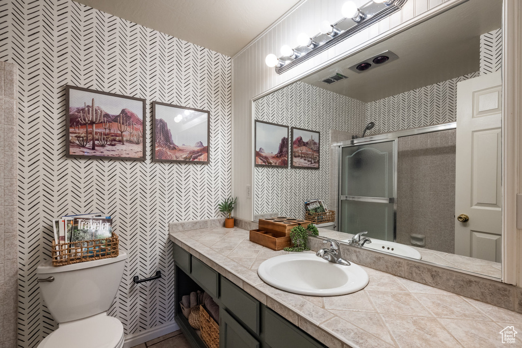 Bathroom featuring wallpapered walls, a shower stall, toilet, and vanity