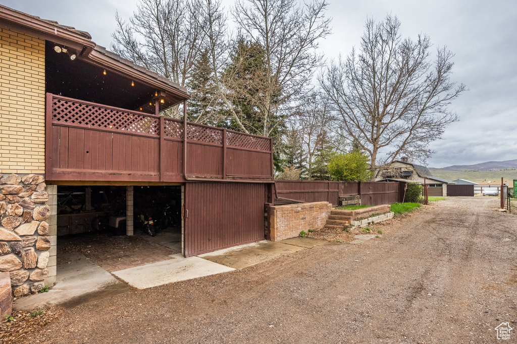 View of home's exterior featuring driveway, a wooden deck, brick siding, and a garage