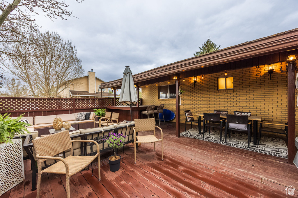 Wooden deck with an outdoor hangout area, outdoor dining area, and fence