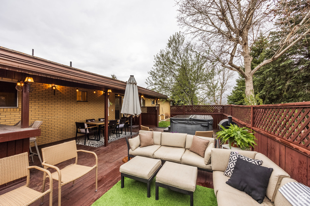 Wooden deck with outdoor dining area, a hot tub, an outdoor living space, and fence