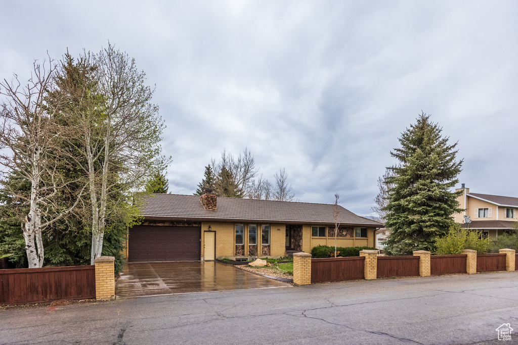 Ranch-style house featuring a garage, asphalt driveway, brick siding, and a tiled roof