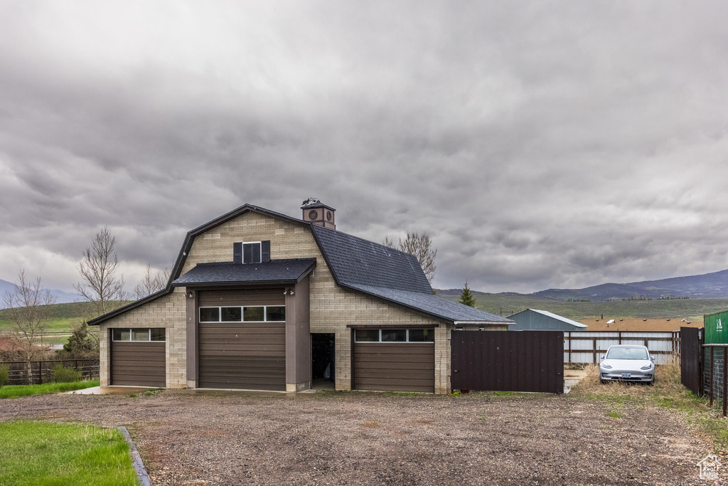 Detached garage featuring fence, a mountain view, and dirt driveway