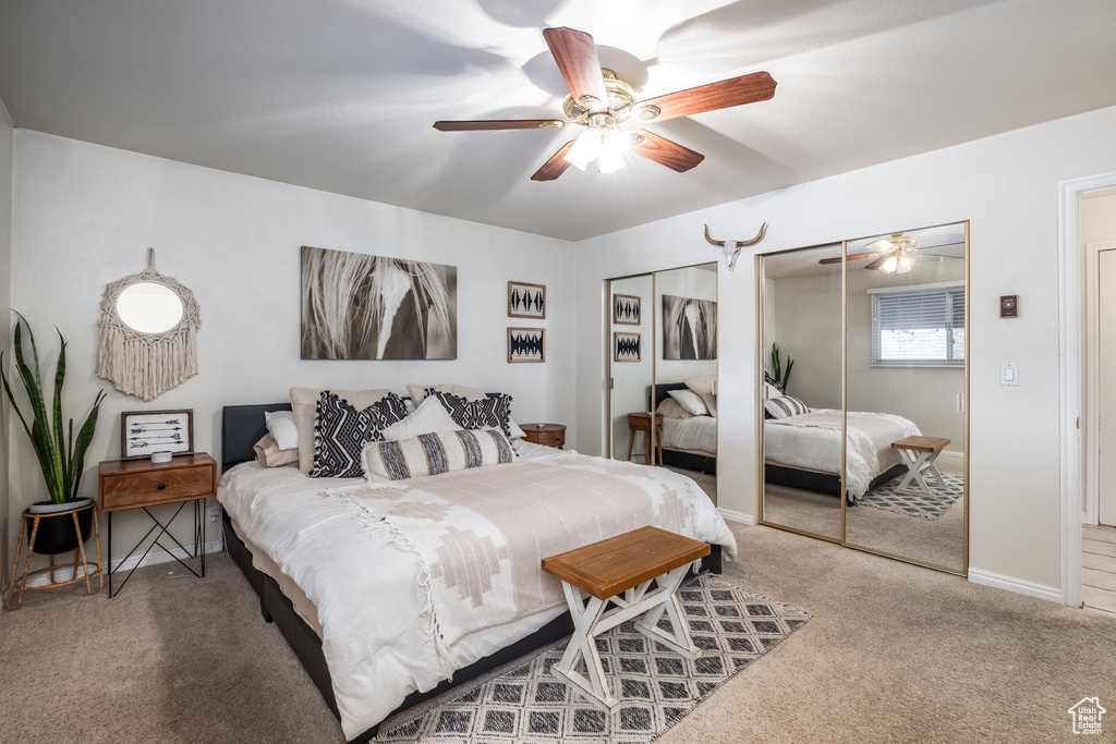 Carpeted bedroom featuring multiple closets, baseboards, and a ceiling fan