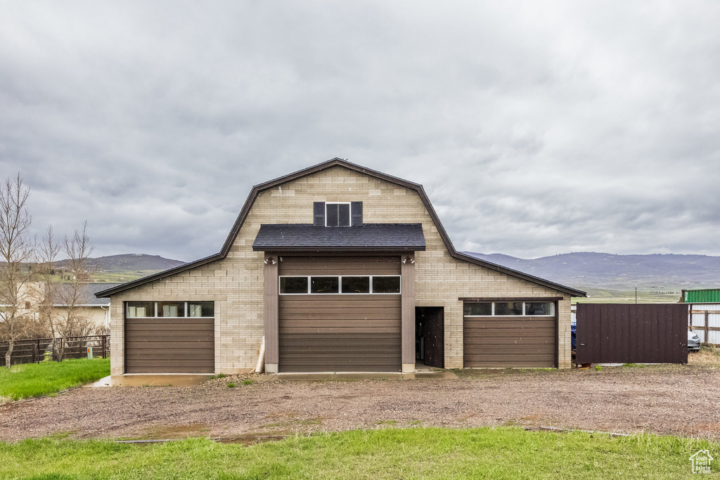 Detached garage featuring fence, a mountain view, and dirt driveway