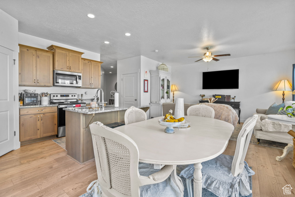 Dining space with recessed lighting, ceiling fan, light wood-type flooring, and a textured ceiling