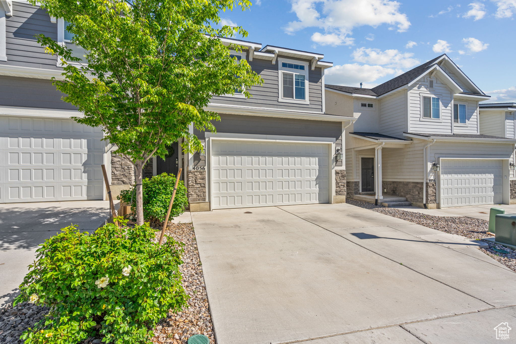 View of front of house with stone siding, concrete driveway, and an attached garage