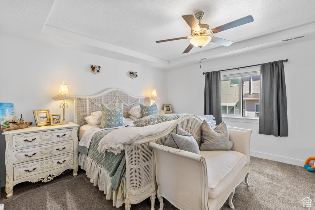 Bedroom with carpet floors, a raised ceiling, baseboards, and a ceiling fan