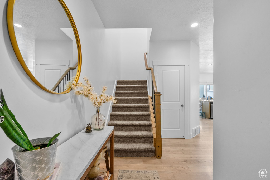 Stairs with wood finished floors and recessed lighting