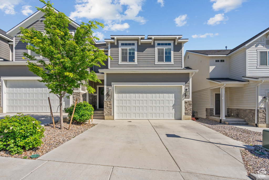 View of front facade featuring a garage, stone siding, and driveway