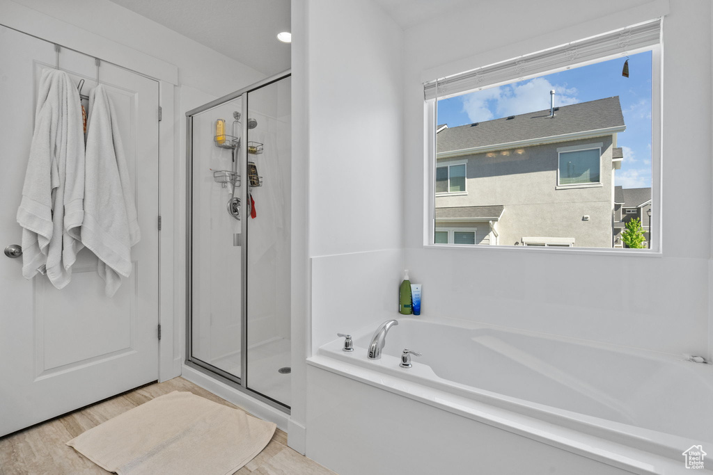 Full bath featuring a stall shower, wood finished floors, and a bath