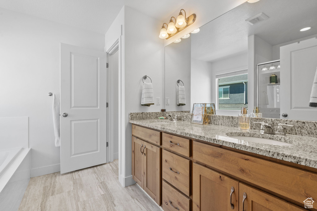 Full bath with double vanity, a shower, a tub, and baseboards