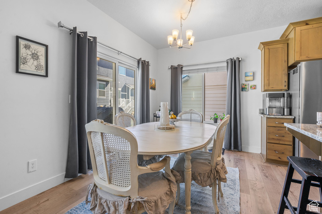 Dining room with a chandelier, light wood-type flooring, and baseboards