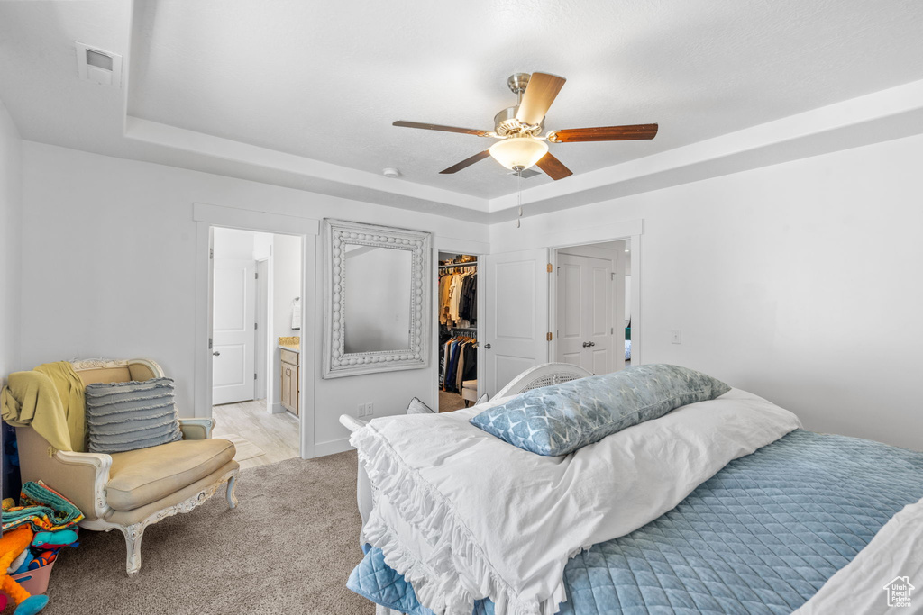 Bedroom featuring a raised ceiling, a spacious closet, a closet, and ensuite bath