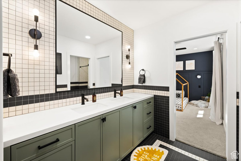 Bathroom with tile walls, tile patterned flooring, double vanity, and connected bathroom