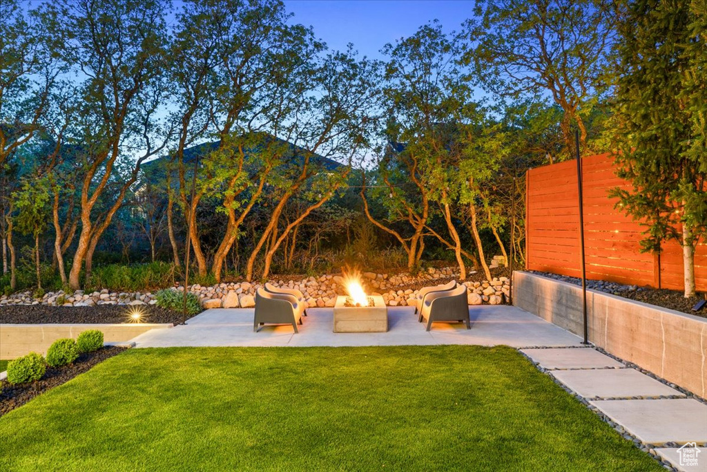 View of green lawn featuring a fire pit, a patio area, and a mountain view