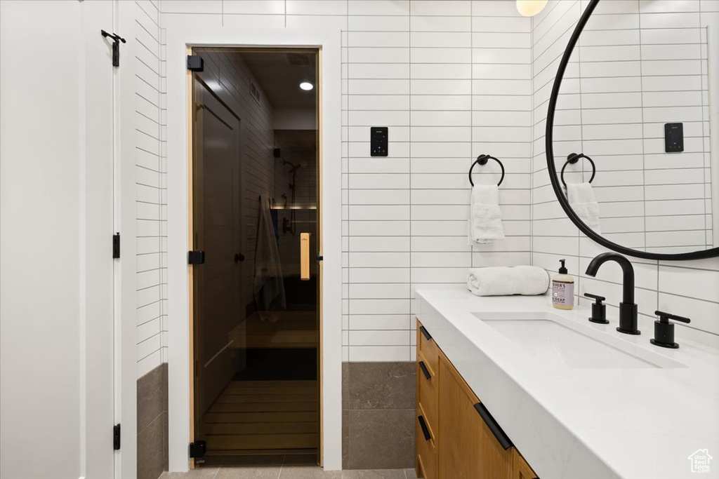 Bathroom featuring tile walls, vanity, tile patterned flooring, and a relaxing sauna