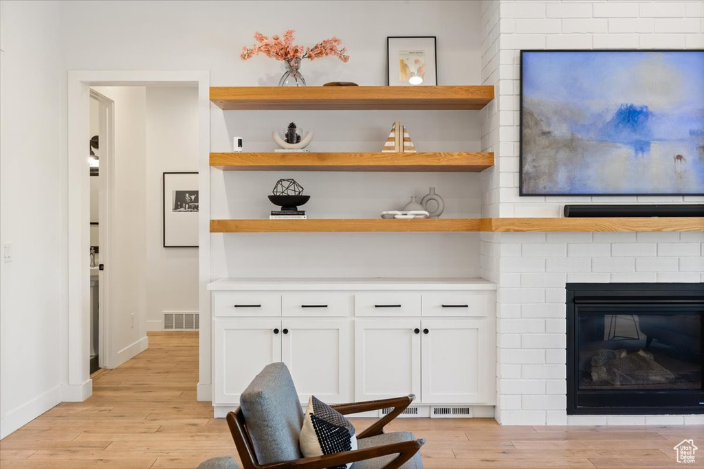 Living area with light wood-style floors, a fireplace, and baseboards