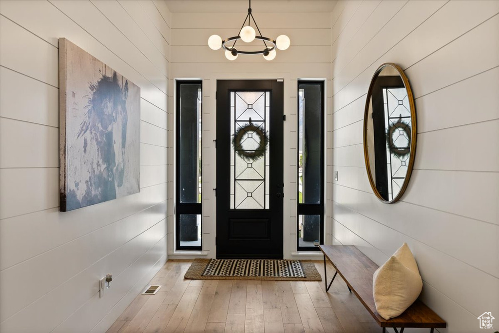 Entrance foyer with hardwood / wood-style flooring, wooden walls, and a chandelier