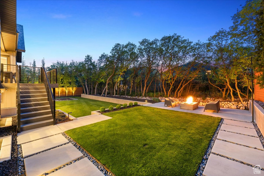 View of grassy yard featuring an outdoor fire pit, a patio, and stairs