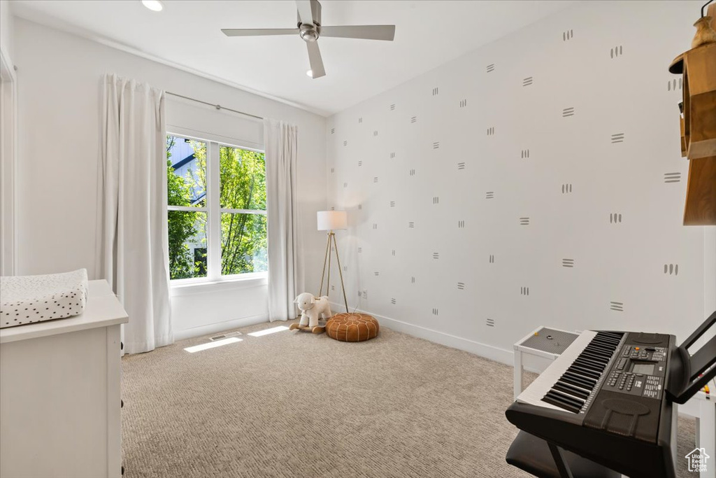 Living area featuring carpet floors, ceiling fan, and baseboards
