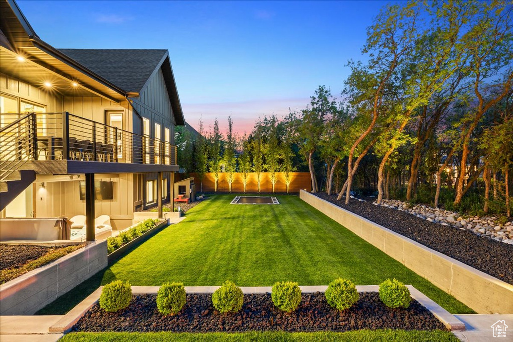 Yard at dusk with a balcony and a patio