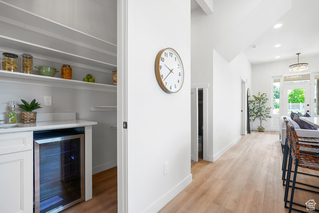 Indoor dry bar with beverage cooler, light wood-type flooring, baseboards, recessed lighting, and hanging light fixtures