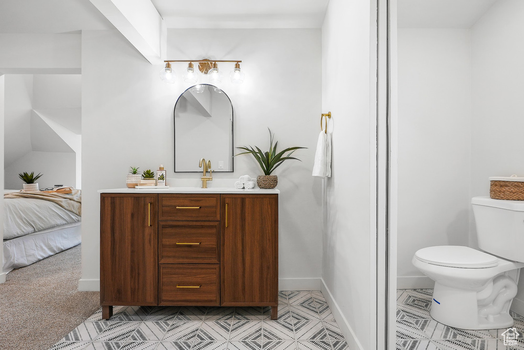 Ensuite bathroom with toilet, vanity, and baseboards