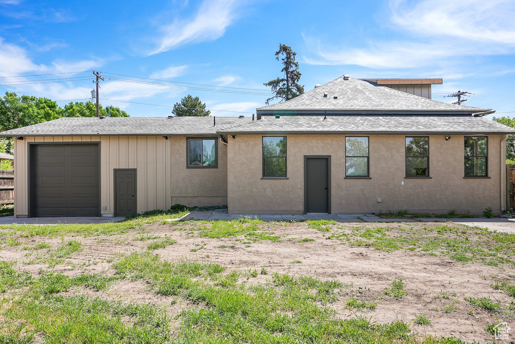 Rear view of property with roof with shingles, a garage, and board and batten siding