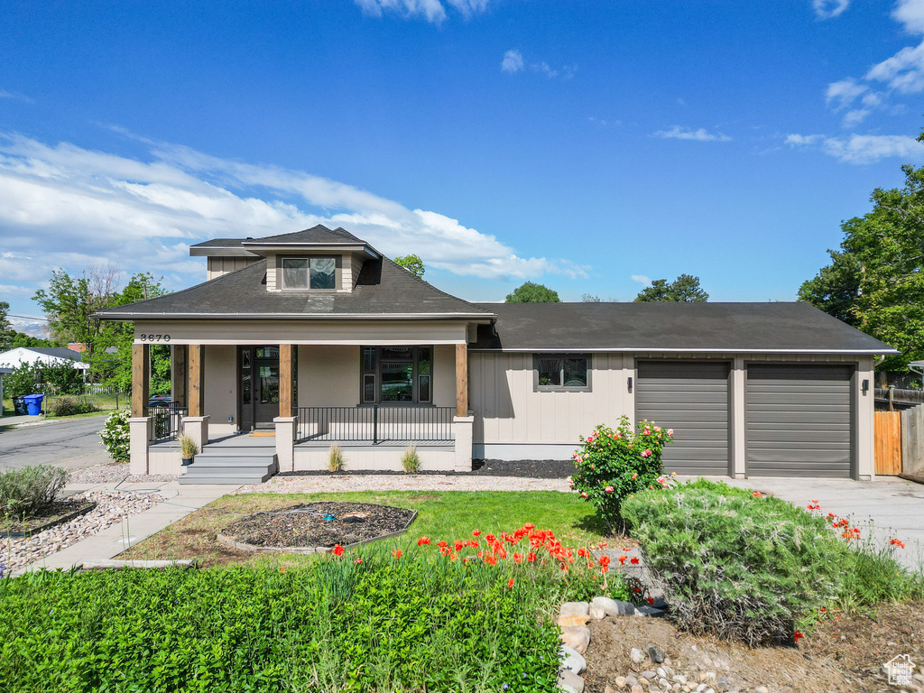 View of front of property featuring an attached garage, a porch, and driveway