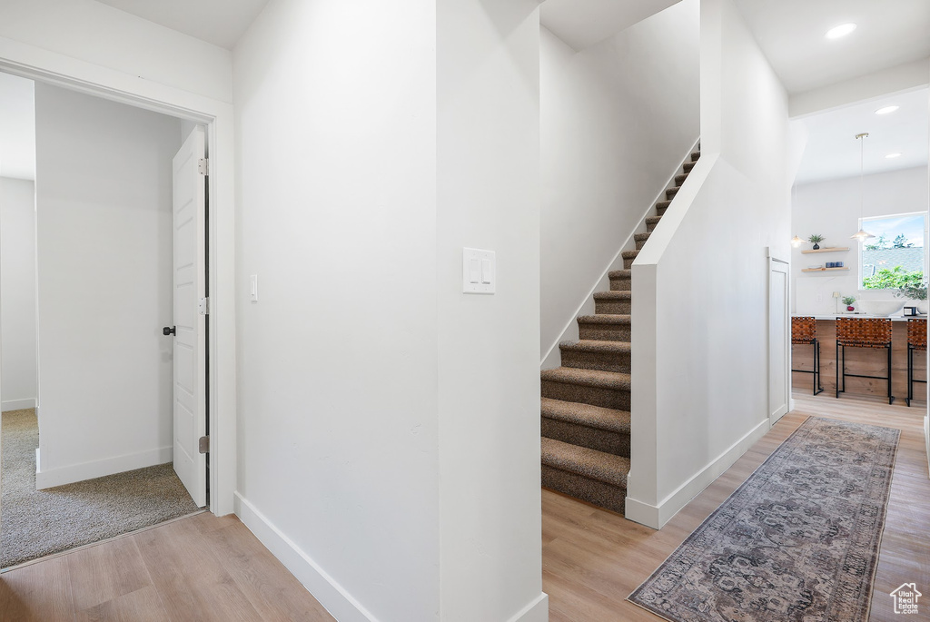 Hall featuring light wood finished floors, stairway, recessed lighting, and baseboards