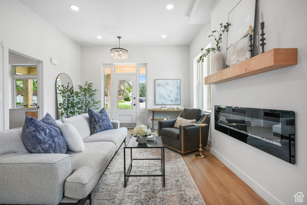 Living room with light wood-style flooring, recessed lighting, baseboards, and a chandelier