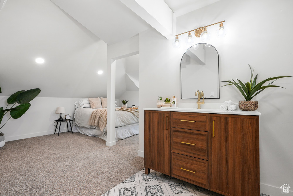 Bedroom with lofted ceiling, light carpet, and a sink