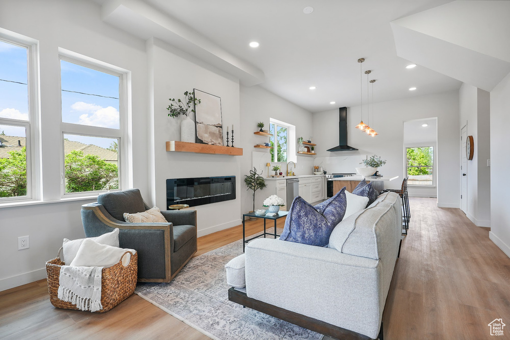 Living room with light wood-type flooring, a glass covered fireplace, baseboards, and recessed lighting