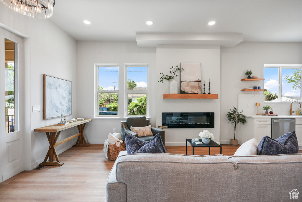 Living area with light wood-type flooring, recessed lighting, a glass covered fireplace, and baseboards