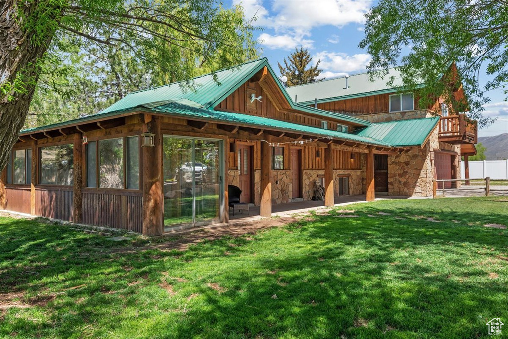 Back of house with stone siding and metal roof