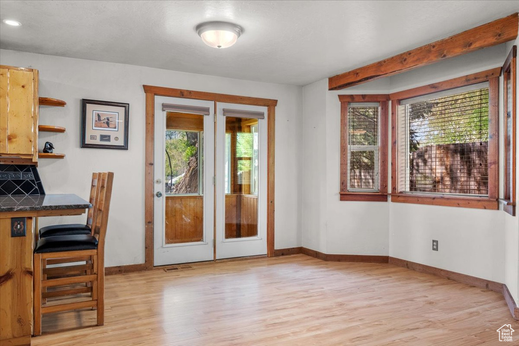 Doorway featuring healthy amount of natural light, light wood-style floors, french doors, and baseboards
