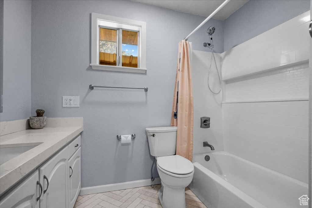 Full bathroom with baseboards, toilet, vanity, and shower / bathtub combination with curtain