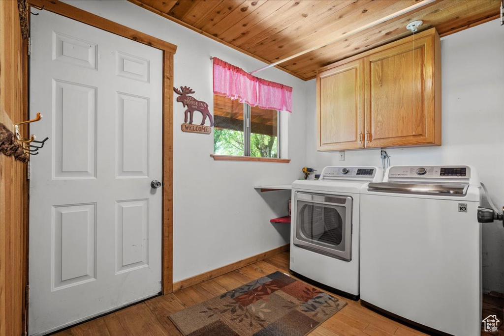 Laundry room featuring cabinet space, independent washer and dryer, wood ceiling, light wood-style flooring, and baseboards