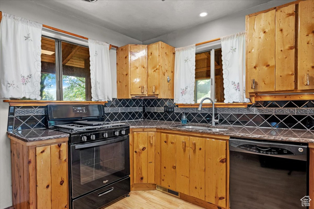 Kitchen with black appliances, a sink, light wood finished floors, healthy amount of natural light, and recessed lighting