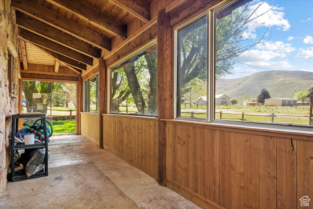 Unfurnished sunroom featuring a mountain view, plenty of natural light, and vaulted ceiling