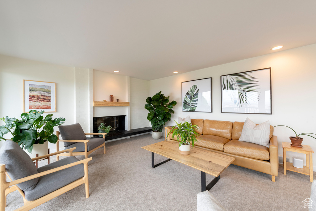 Living room featuring recessed lighting, carpet, and a fireplace with raised hearth