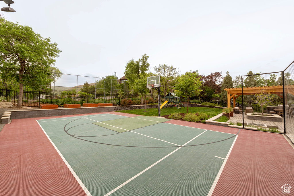 View of basketball court with community basketball court, fence, and healthy amount of natural light