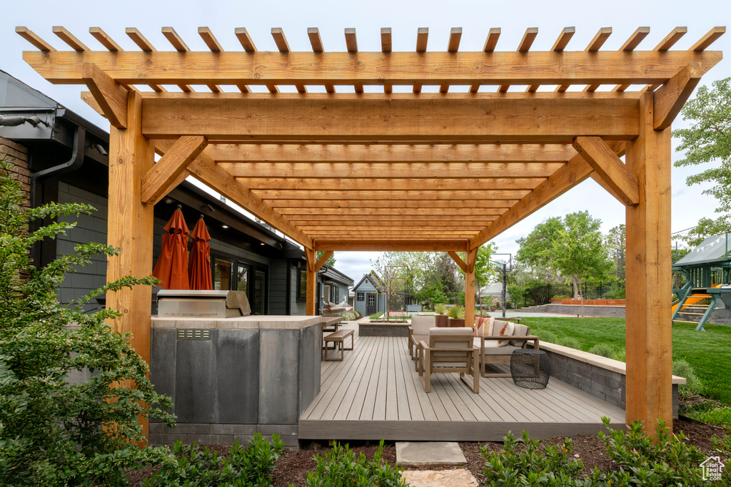 Deck with a pergola, a lawn, and area for grilling