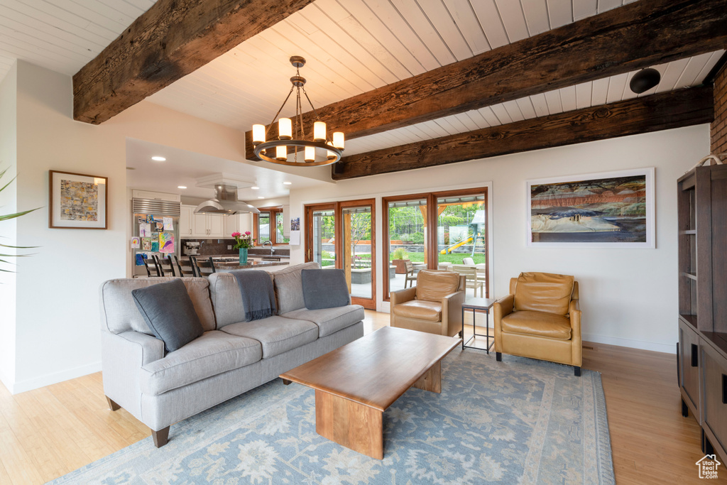 Living area featuring a chandelier, light wood-style floors, wood ceiling, baseboards, and beam ceiling